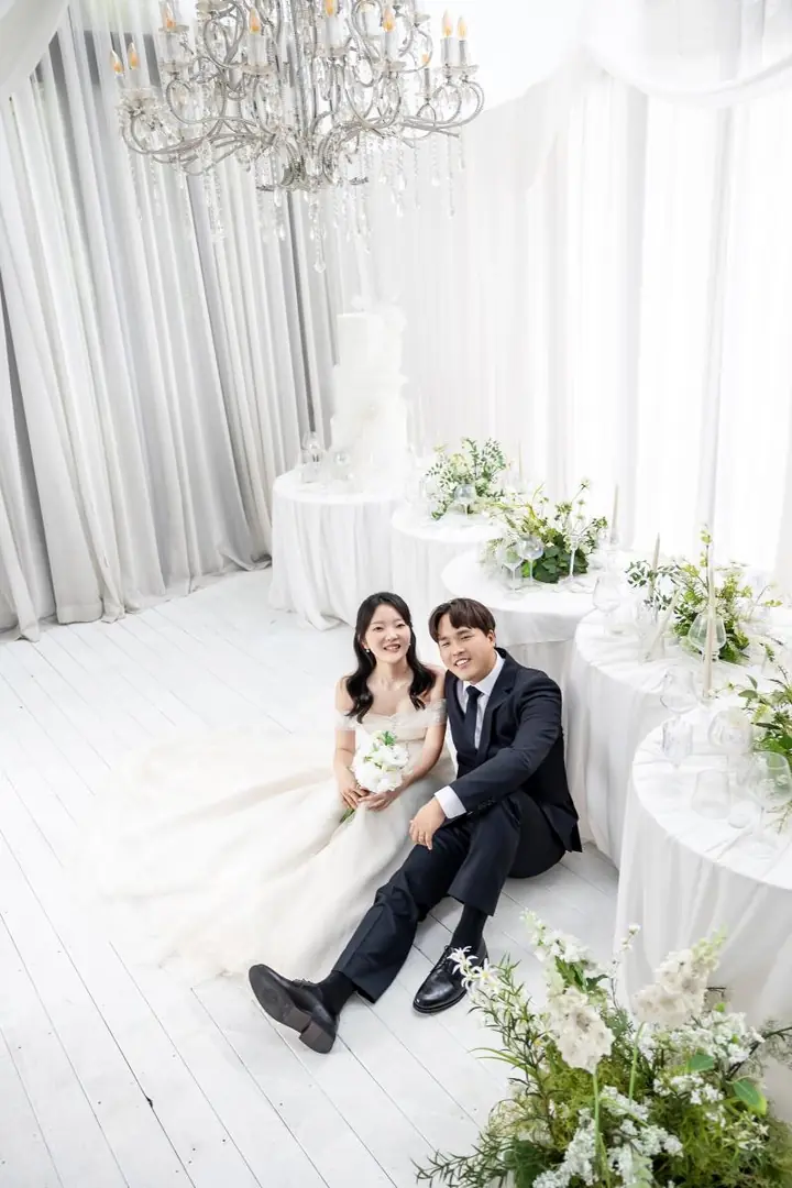 샹들리에 아래 바닥에 나란히 앉은 두 사람