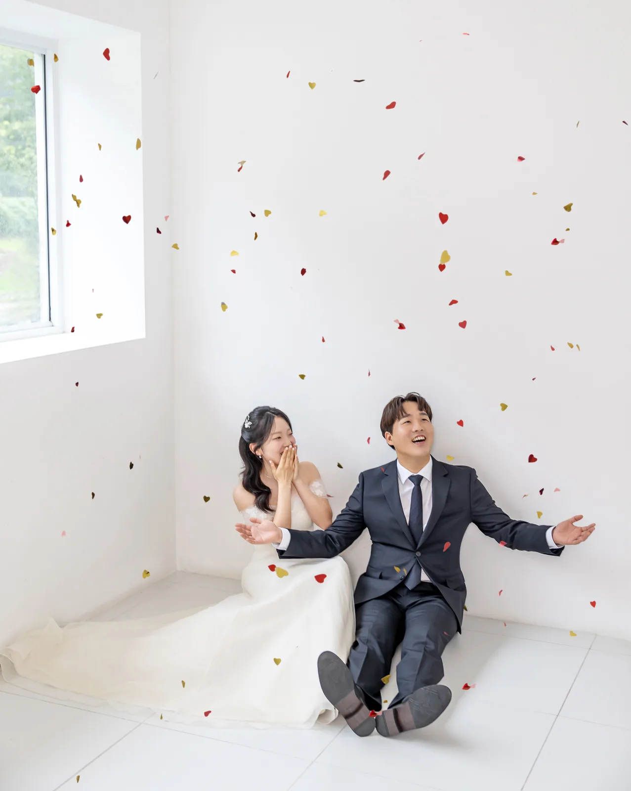 꽃잎이 흩날리는 하얀 방에 앉은 두 사람