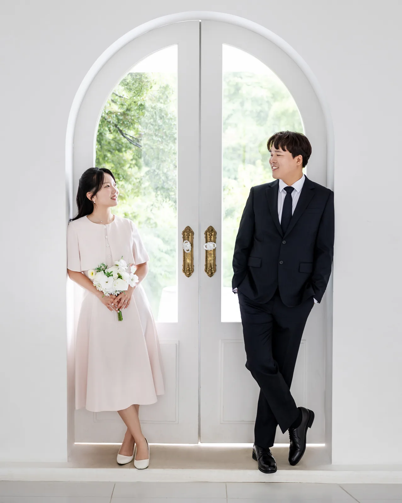 하얀 아치 창문 앞에 선 두 사람