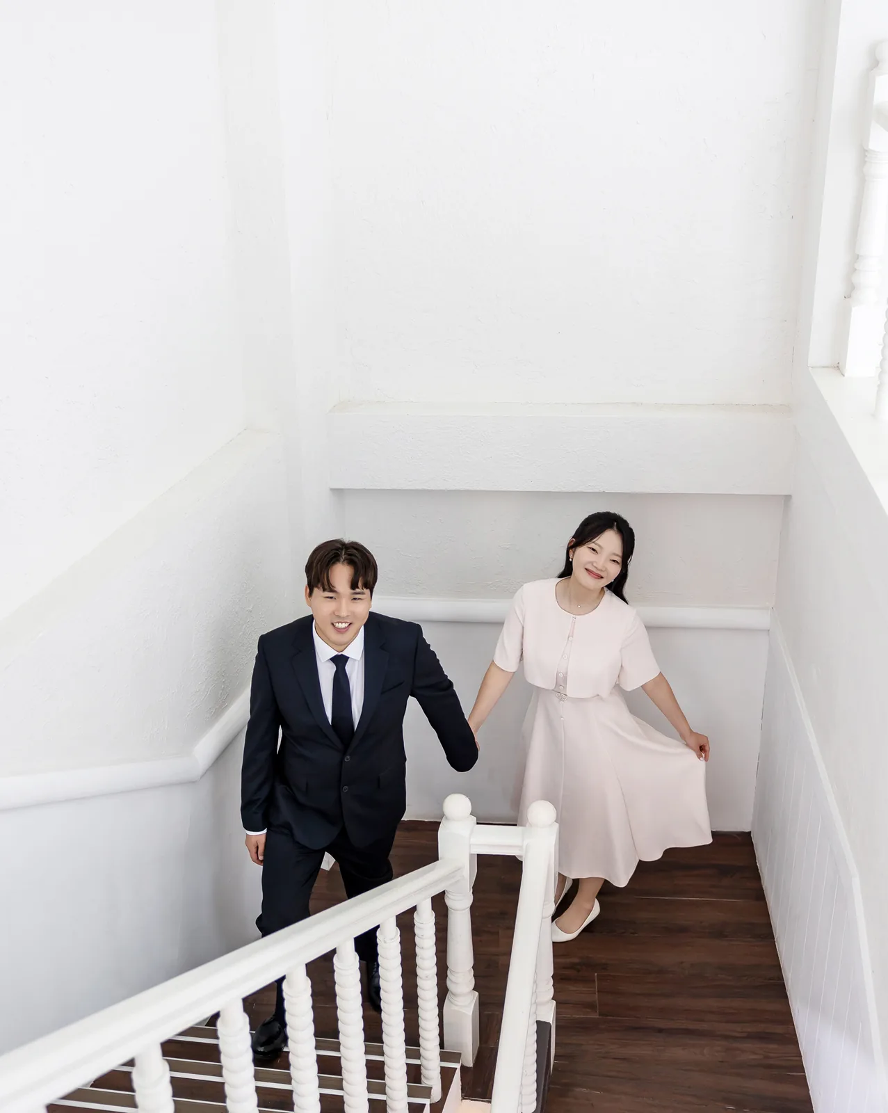 하얀 계단에서 손잡고 내려오는 두 사람