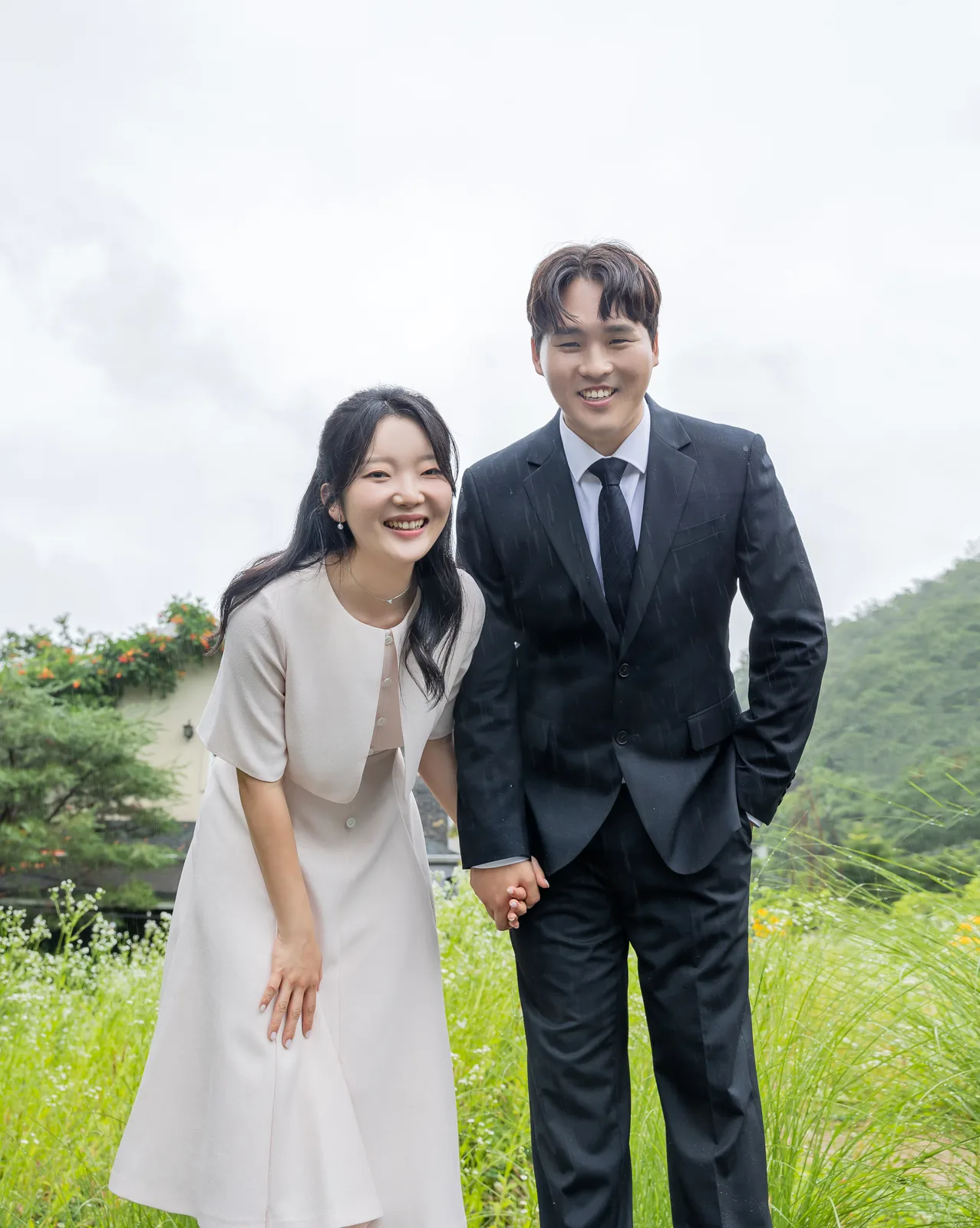 초록 언덕 앞에서 웃는 두 사람